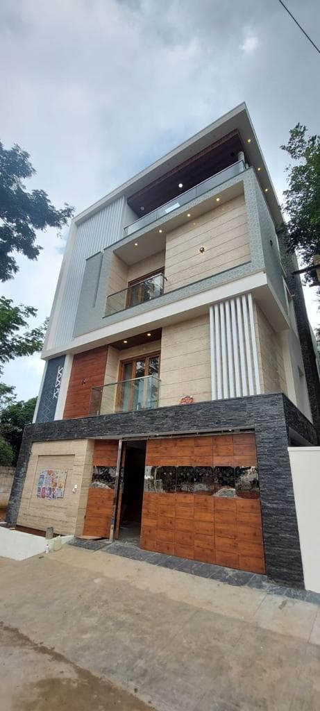 Four-storey independent house with wood-finish cladding and glass balconies, built by ACIPL