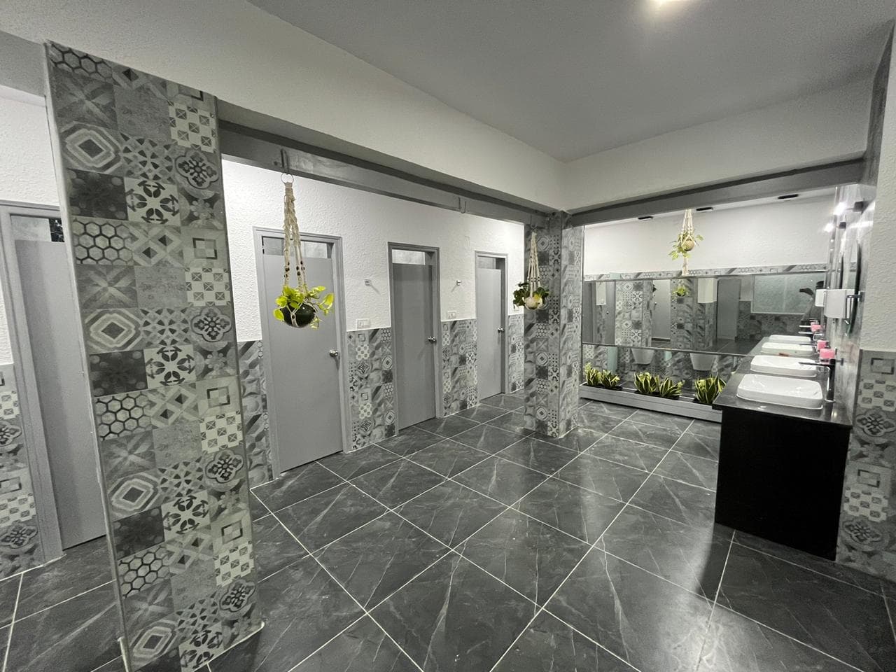 Renovated washroom with patterned grey wall tiles and a vanity counter at Century Club, Bengaluru, by ACIPL