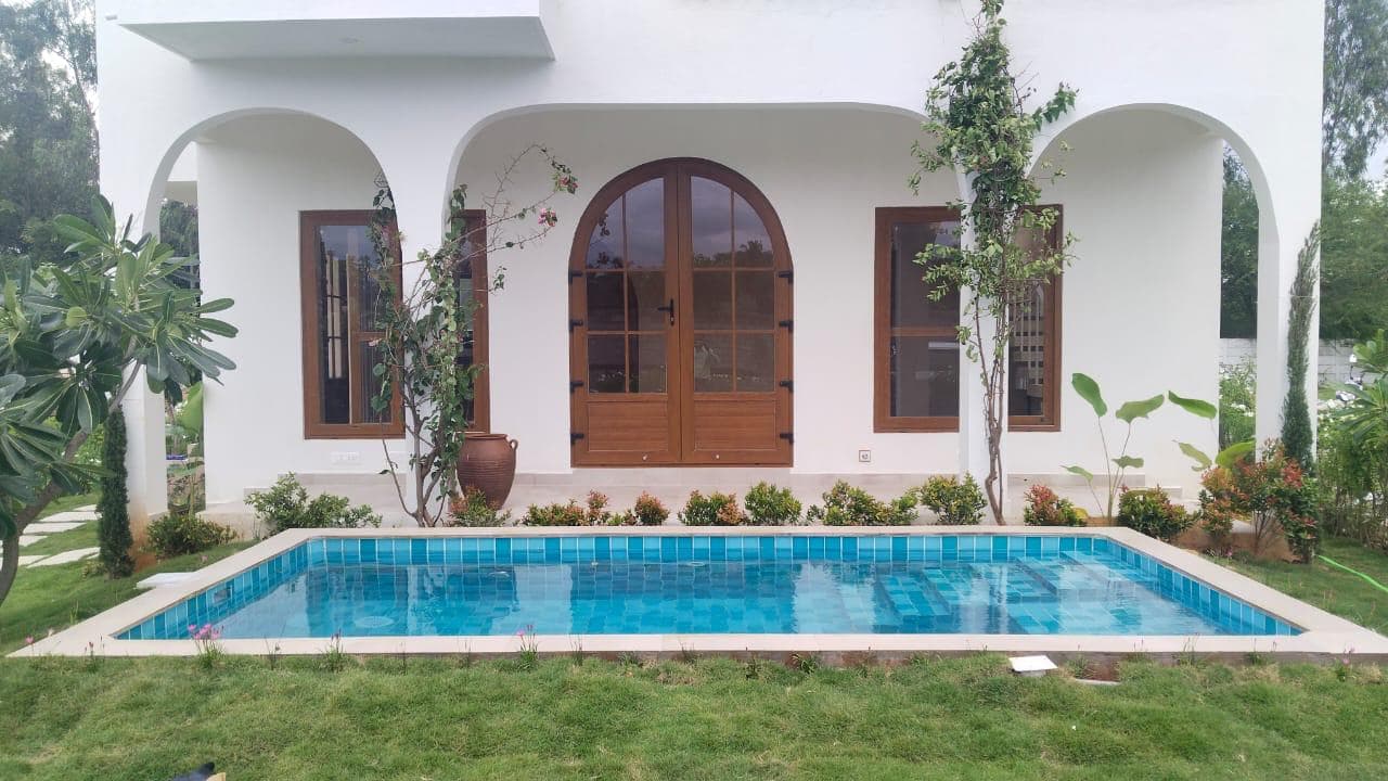 Villa with arched verandas and a swimming pool in a landscaped garden, built by ACIPL